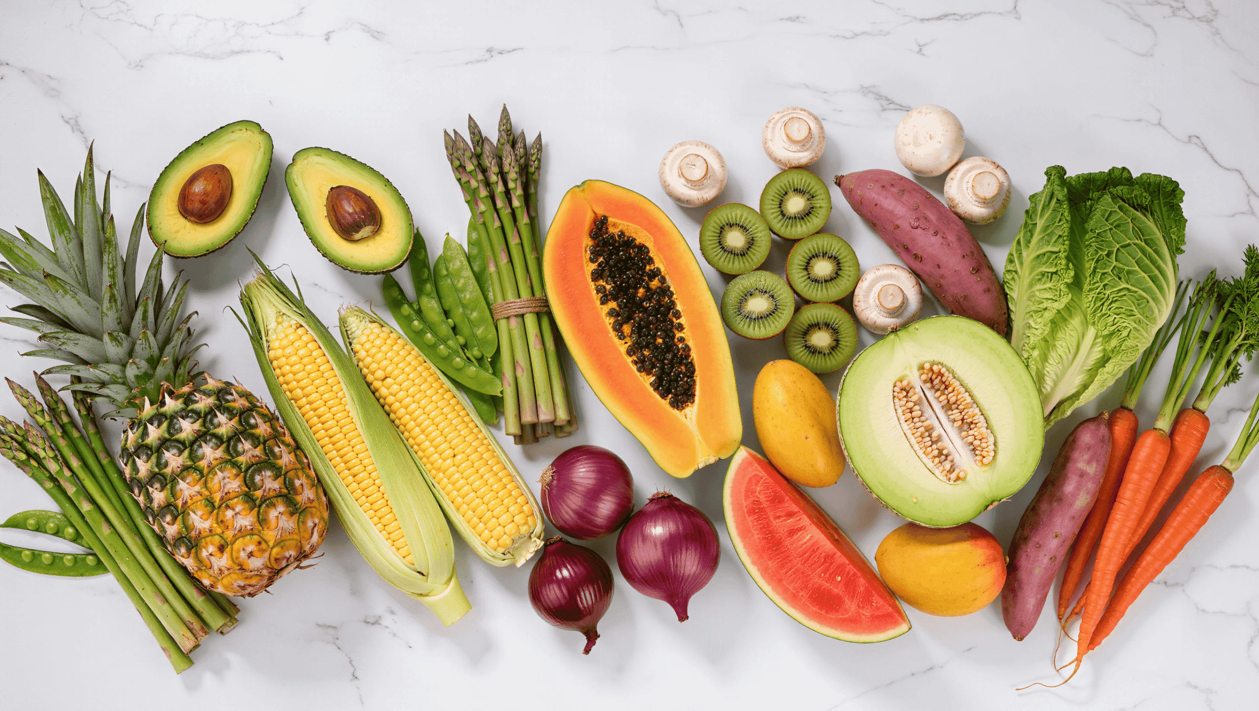Fresh Clean Fifteen produce including avocados, pineapple, sweet corn, onions, papaya, asparagus, honeydew, kiwi, cabbage, mushrooms, mangoes, sweet potatoes, watermelon, and carrots